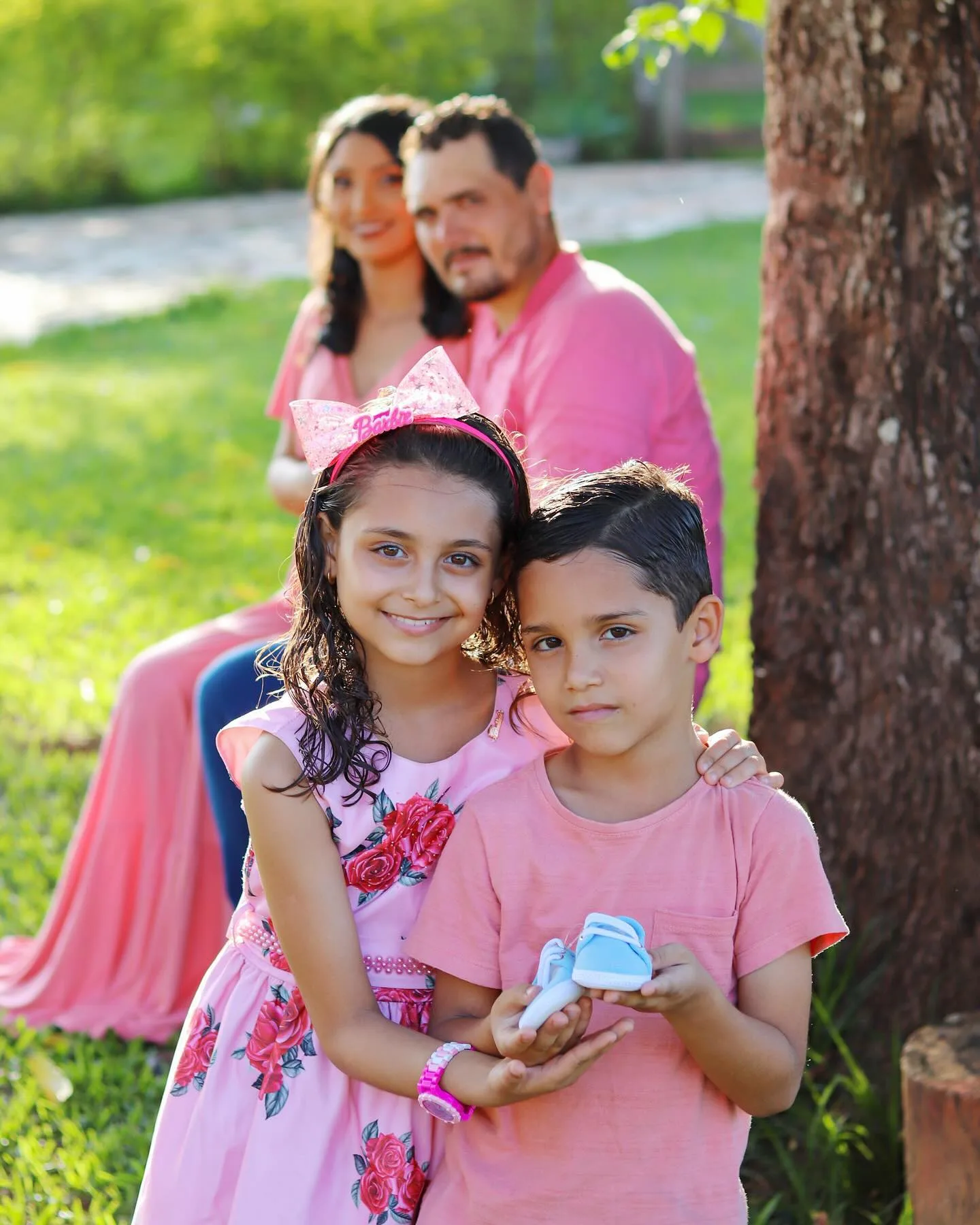 Família com duas crianças e roupas em tons de rosa em um parque