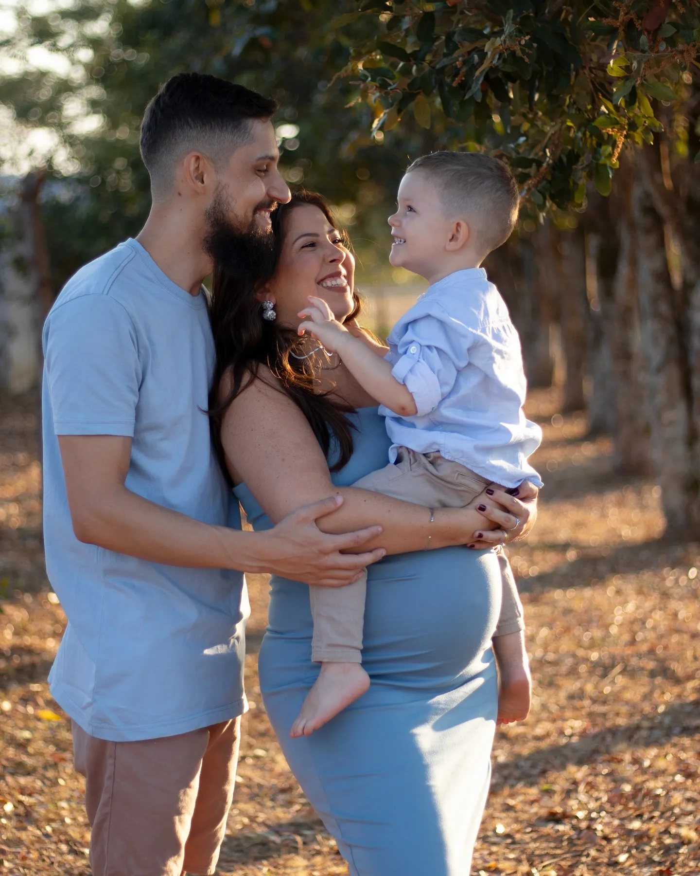 Família com uma criança no colo junto a árvores, em luz de fim de tarde