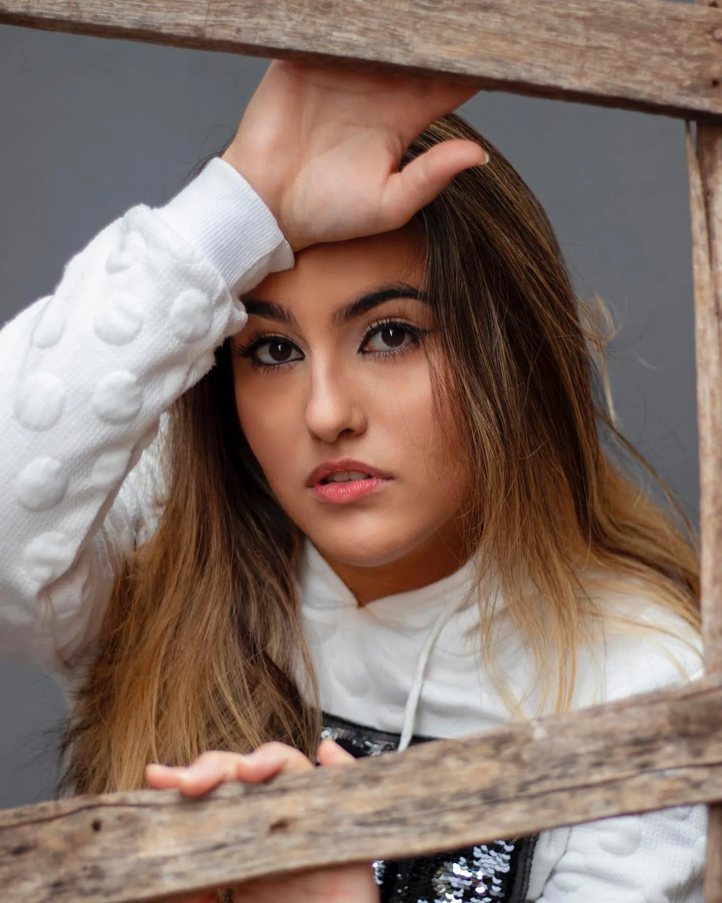 Retrato de mulher de blusa branca entre peças de madeira